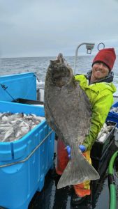 Jason Kusiak standing in front of the ocean holding a very large fish