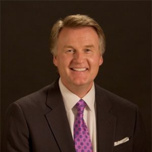 Phil Styrlund, smiling, wearing a suit and purple polka-dot tie