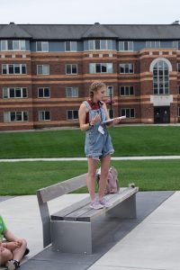 Photo of Grace P standing on a bench outside