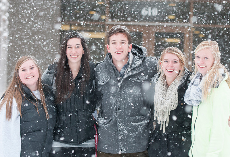 Students pose during a snowfall on campus