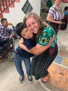 young woman hugs a small child while they smile at the camera