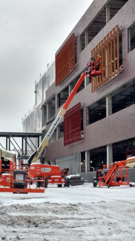 Construction crews install the accent-colored window frames on the Hagfors Center.