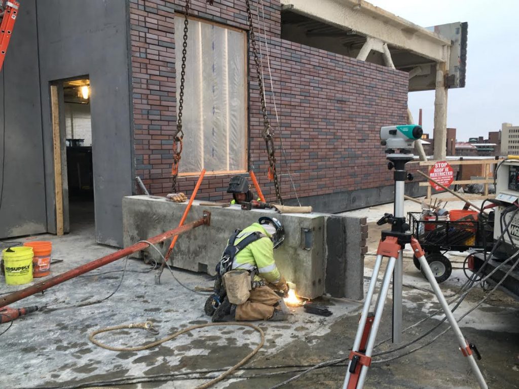 A crew member works on the south end of the fourth floor roof, where the roof-top greenhouse will ultimately be located. 