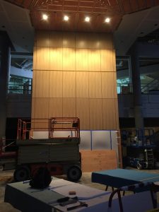 Ceiling lights illuminate the wood wall in the lobby