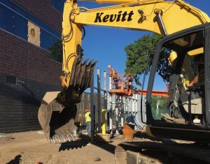 A back hoe digs a footing for a screen post.