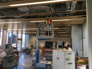 Man in lift installing wood ceiling slats