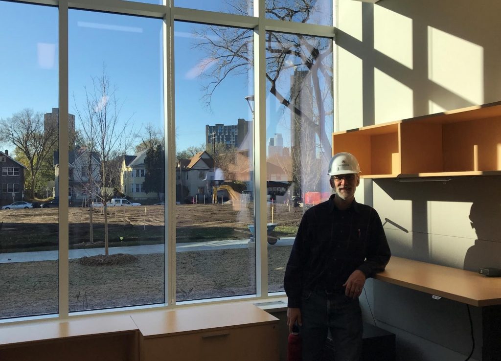 Stu Anderson in safety vest and hard hat standing in new office