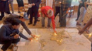 Ceremony attendees light the world map with candles