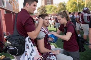 Student Sports Medicine Assistants Jack Duffy ’16 (left) and Alison Ranum ’17 (right) aid Auggie running back Michael Busch ’16.