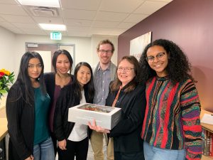 group of five students with Sandy who is holding a cake