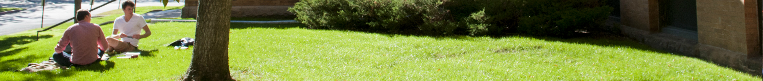 Two students sitting on lawn on campus